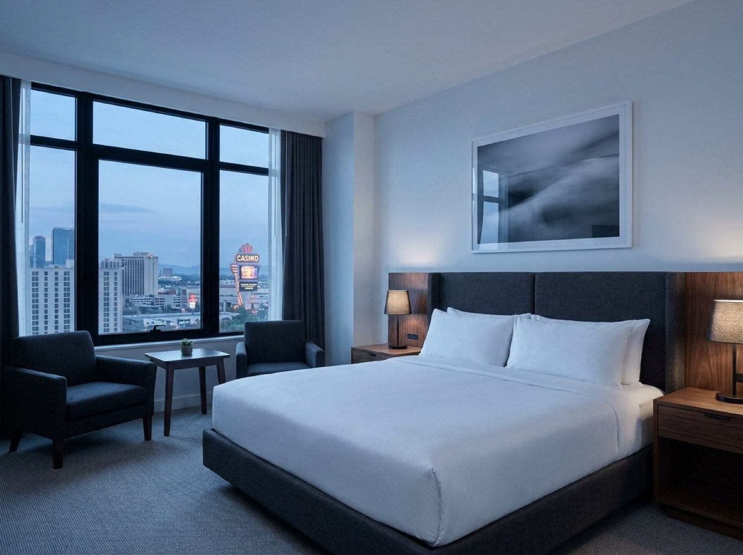 PartyQueueCrew suite interior — king bed, charcoal upholstery, city window